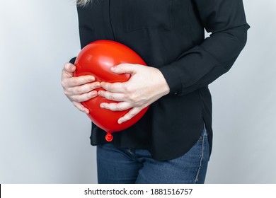 Bloating and flatulence concept. The woman holds a red balloon near the abdomen, which symbolizes bloating. Intestinal tract and digestive system. Problems with flatulence adn gastrointestinal tract
