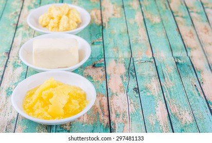 A Block Of Butter, Margarine And Ghee In White Bowls Over Rustic Wooden Background