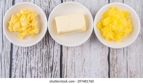 A Block Of Butter, Margarine And Ghee In White Bowls Over Rustic Wooden Background