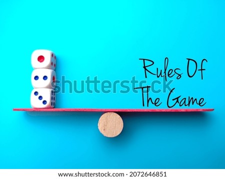 Block cylinder center between white dice and text Rules Of The Game.