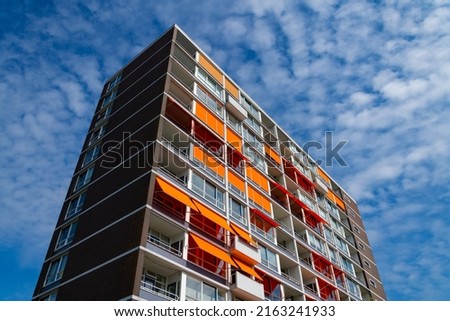 Block of Flats apartment house in Rotterdam Netherlands with Balconys, windows and orange awnings. Background with elements of a typical building from the Sixties and Seventies from frog perspective.