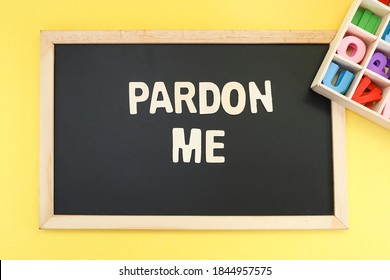 Block Letters Message On Pardon Me On Black Chalkboard With Colorful Letters On Wooden Container 