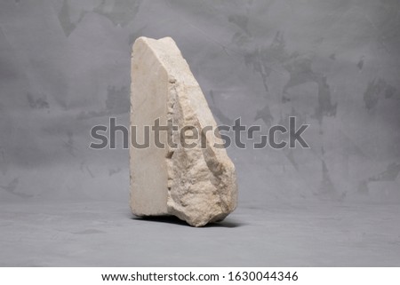 Block of marble rock on gray neutral painted background, minimalist decor