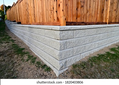 block retaining wall, block wall with fence, corner section block wall, cement blocks, gray, wooden fence,  - Shutterstock ID 1820403806