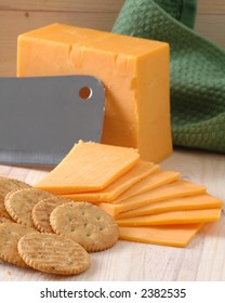 A Block Of Sliced Cheddar Cheese And Whole Wheat Crackers