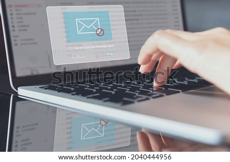 Blocking spam e-mail, warning pop-up for phishing mail, network security concept. Business woman working on laptop computer at home with warning window on screen