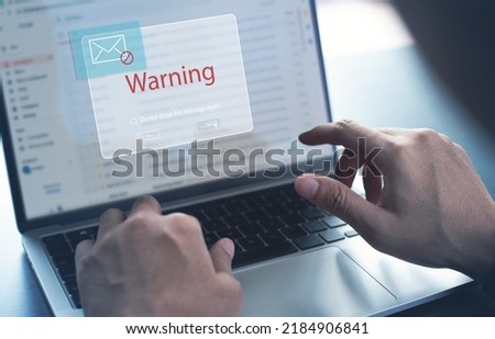 Blocking spam e-mail, warning pop-up for phishing mail, network security concept. Business man working on laptop computer at home with warning window on screen