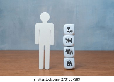 Blocks with basic human needs icons symbolizing shelter, clothes, food, and medicine beside a human figure. Essential life requirements, human rights, and social welfare concept.