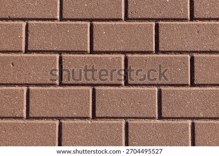 Blocks of concrete that are both rectangular and reddish, like actual bricks; a closeup