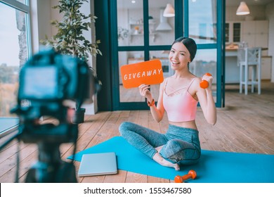 Blogger doing giveaway. Cheerful famous fitness blogger wearing short top doing giveaway in her blog - Shutterstock ID 1553467580