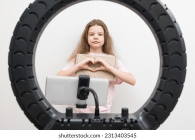 blogger girl shows a parcel in front of the phone making a heart with her hands , a view from the front - Shutterstock ID 2313403545