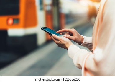 blogger hipster using in hands gadget mobile phone, woman texting message on blank screen smartphone, texting message, mockup online wifi internet concept, hipster waiting on station platform on back