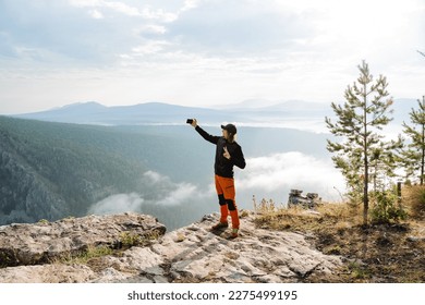 The blogger shoots content, traveling through the mountains, photos on the phone, selfie yourself, a rocky cliff, face photography. High quality photo - Powered by Shutterstock