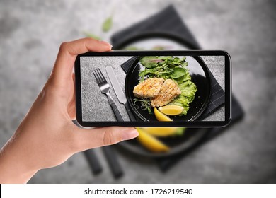 Blogger Taking Picture Of Delicious Grilled Fish At Table, Closeup. Food Photography