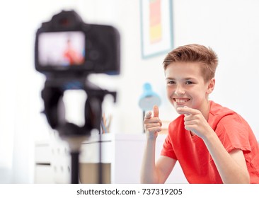 blogging, technology and people concept - happy smiling boy or blogger with camera recording video at home