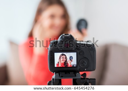 blogging, technology, videoblog, makeup and people concept - happy smiling woman or beauty blogger with eyebrow pencil, mirror and camera recording tutorial video at home