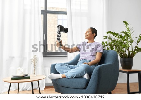 blogging, videoblog and people concept - happy smiling african american female video blogger with camera videoblogging at home