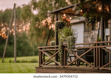 Blome, Latvia - September 11, 2023 - Cozy gazebo with hanging plants and string lights at sunset, surrounded by lush greenery, creating a serene and inviting outdoor space. Copy space. - Powered by Shutterstock