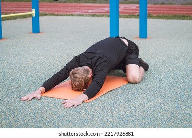 blond athlete warms up and breathes his body in the child's pose, which is part of the sun salutation in the yoga. Warming up important muscle groups. - Powered by Shutterstock