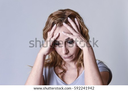 blond attractive woman on her thirties sad and depressed looking desperate in sorrow and grief facial expression in female depression emotion concept isolated on grey background