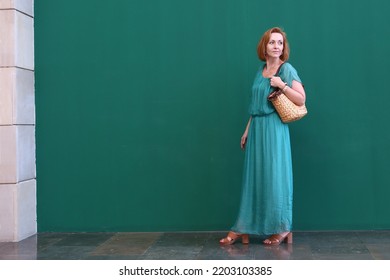 Blond Beautiful Woman In Blue Dress Close Up Portrait On Green Wall Background