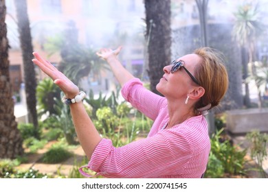 Blond Beautiful Woman In Sun Glasses Enjoy Water Mist On Hot Day On Downtown Square In Valencia Close Up Photo