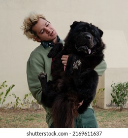 Blond Boy Carrying His Big Black Dog In A Funny Way