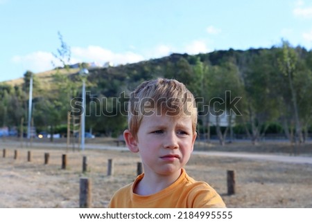 A blond boy with a disgruntled expression on his face. A five-year-old boy in a bad mood. 
