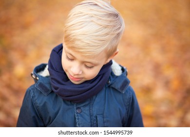 Blond Boy With Long Hair. School Child In Autumn Park. Close Horizontal Portrait Not Looking At The Camera