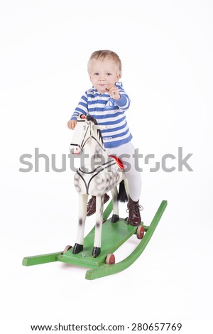 Blond boy riding wooden rocking horse