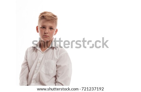Blond boy in white shirt and black pants posing on white background