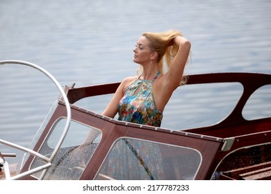 Blond caucasian woman driving a sport motor boat on a lake at summer