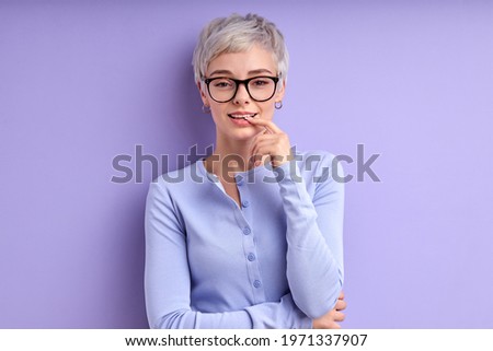 Blond caucasian woman with short hair teasing with finger on mouth isolated on purple