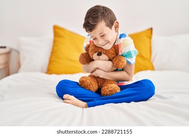 Blond child hugging teddy bear sitting on bed at bedroom - Powered by Shutterstock