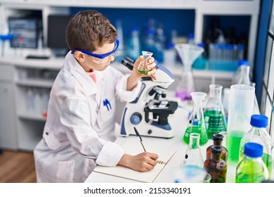 Blond child wearing scientist uniform writing on notebook at laboratory - Powered by Shutterstock