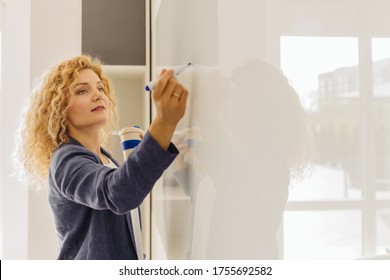 Blond Curly Business Woman Or Teacher Writing In Flipchart. Close Up, Side View, Copy Space Text. Female Preparing A Presentation In A Conference Or Meeting Setting.