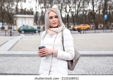 Blond Dreaming Squinted Woman, Walking In City, Fashion Trendy Outfit Warm Jacket, Leather Bag Pack, Drinking Tea In Cup, Trees Cars Park Plants Road. Urban Touristic Center, Weekend Activity, Day