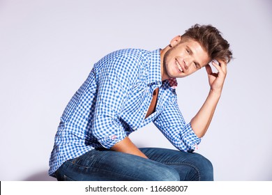 Blond Fashion Male Model Sitting And Laughing On Gray Background