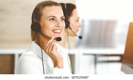 Blond female customer service representative is consulting clients online using headset in sunny office. Call center concept - Shutterstock ID 1879159687