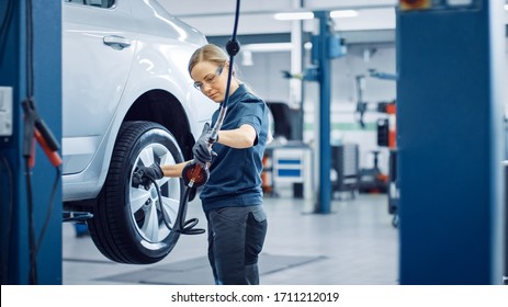 Blond Female Mechanic is Checing the Tire Pressure in a Wheel of a Vehicle. Empowering Woman Works in a Modern Clean Car Service. Specialists Inflates the Wheel After Fixing a Component on a Vehicle. - Powered by Shutterstock