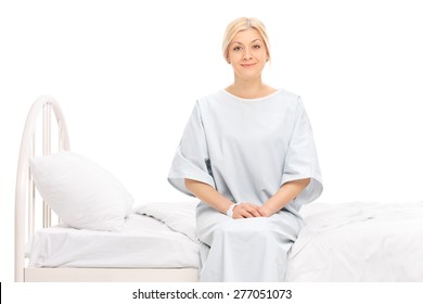 Blond female patient sitting on a hospital bed and looking at the camera isolated on white background - Powered by Shutterstock