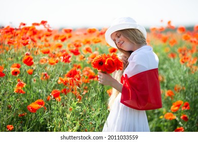 Blond girl covered with flag of Poland holding bouquet of poppies in the poppy field. Polish Flag Day. Independence Day. Love Poland concept. Selective soft focus. - Shutterstock ID 2011033559