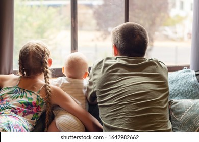 A blond girl, her baby brotherand their father looking through the window. Family concept - Shutterstock ID 1642982662