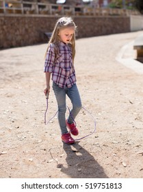 Blond Girl Jumping Rope In Park