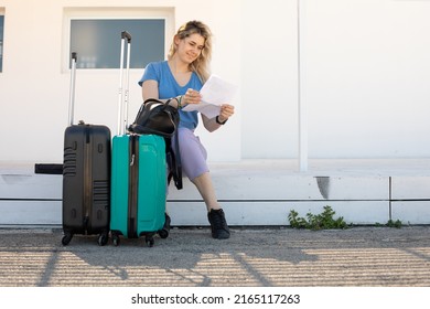 Blond Glad Woman With Baggage Sitting Near Railway Station, Waiting For Transport. Start New Life Abroad. Check-in Sheet