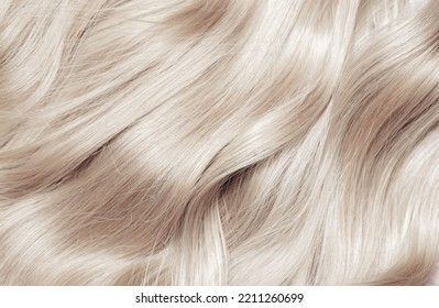 Blond hair close-up as a background. Women's long blonde hair. Beautifully styled wavy shiny curls. Hair coloring. Hairdressing procedures, extension. White hair - Shutterstock ID 2211260699