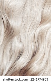 Blond hair close-up as a background. Women's long blonde hair. Beautifully styled wavy shiny curls. Hair coloring. Hairdressing procedures, extension. White hair - Shutterstock ID 2241974983