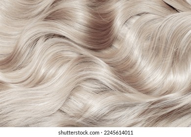 Blond hair close-up as a background. Women's long blonde hair. Beautifully styled wavy shiny curls. Hair coloring. Hairdressing procedures, extension. White hair - Shutterstock ID 2245614011