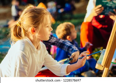Blond haired teenager school girl drawing beautiful picture outdoor in the park at lake shore  Open air activity for school age children concept 