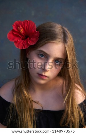 Blond kid girl portrait with hibiscus red flower on hair